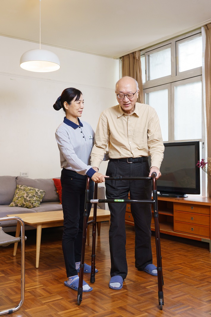 家庭托顧服務，由照顧服務員協助長輩在家中使用輔具行走。